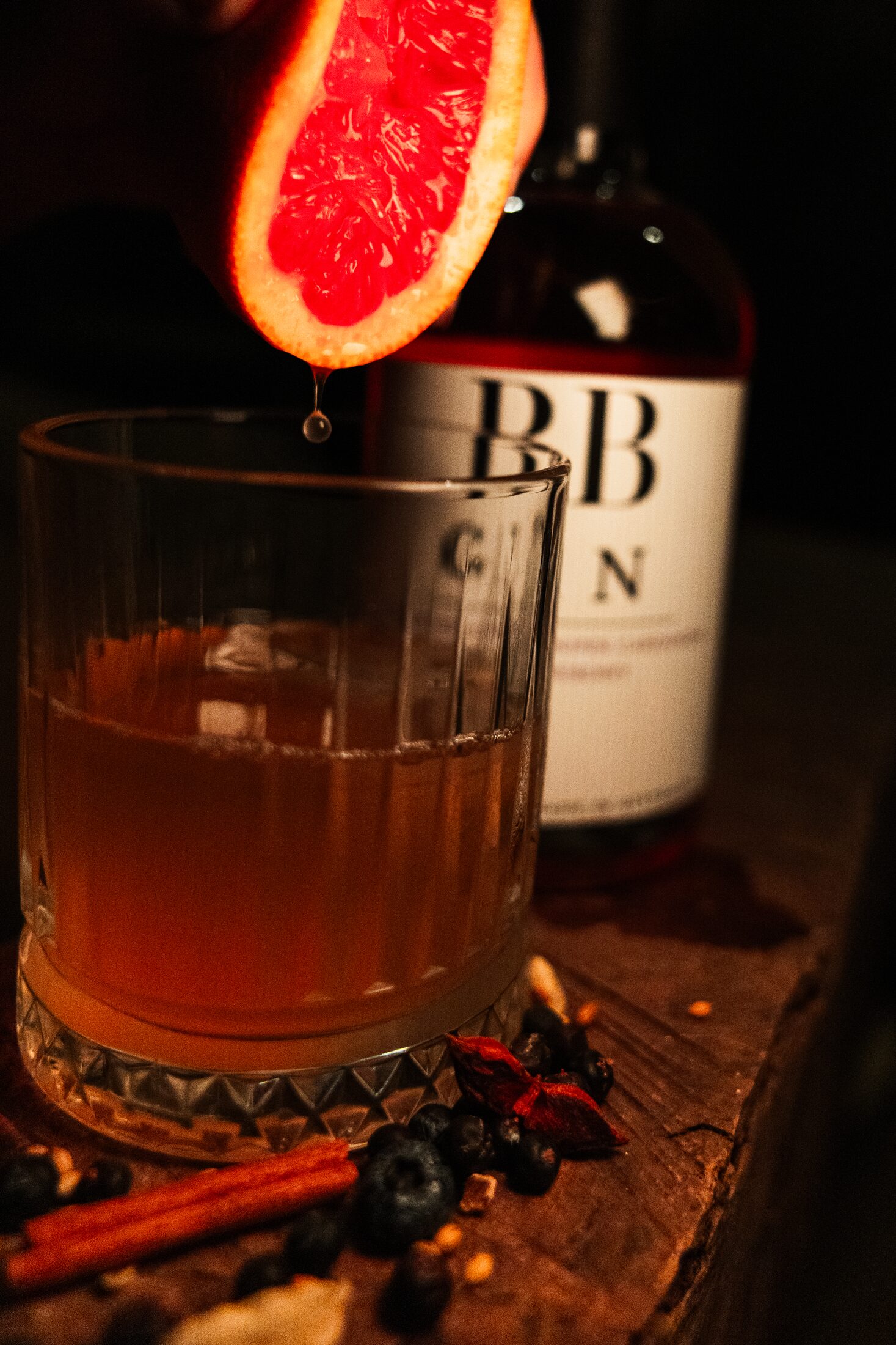 Squeezing blood orange into a glass of BB Gin